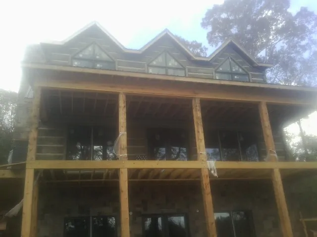 Dormers and porch framing on a large log home under construction — Roof Coating work by our crew in Hobart